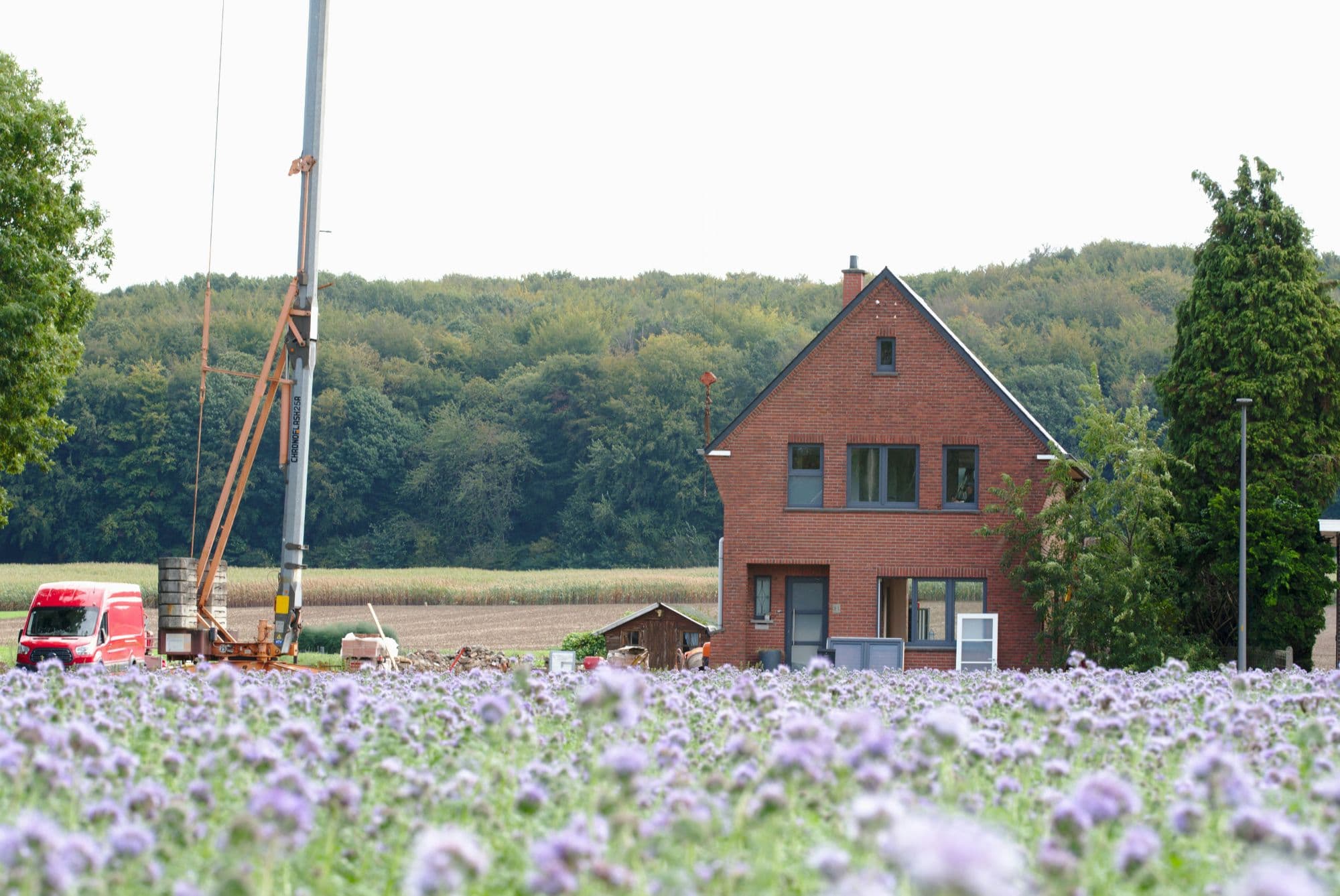 Einfamilienhaus aus Klinker mit Baukran auf dem Nachbargrundstück